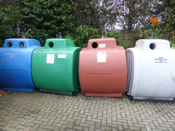 Blue, green, red and white recycling containers outdoors.