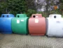 Blue, green, red and white recycling containers outdoors.