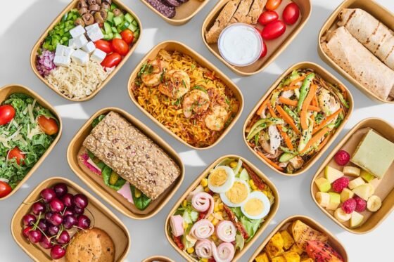 Overhead arrangement of prepared meals, salads, wraps, fruit and breakfast dishes.