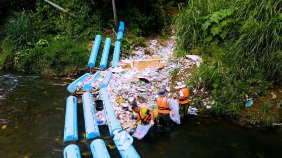 Workers remove captured material beside a river interception barrier in the supplied Panama City project photographs.