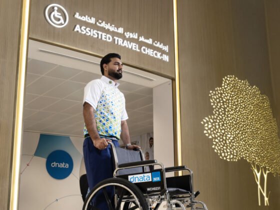 A dnata staff member stands with a wheelchair at the assisted-travel check-in entrance