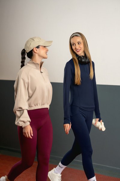 Two models walking indoors in burgundy leggings and navy fitted activewear.