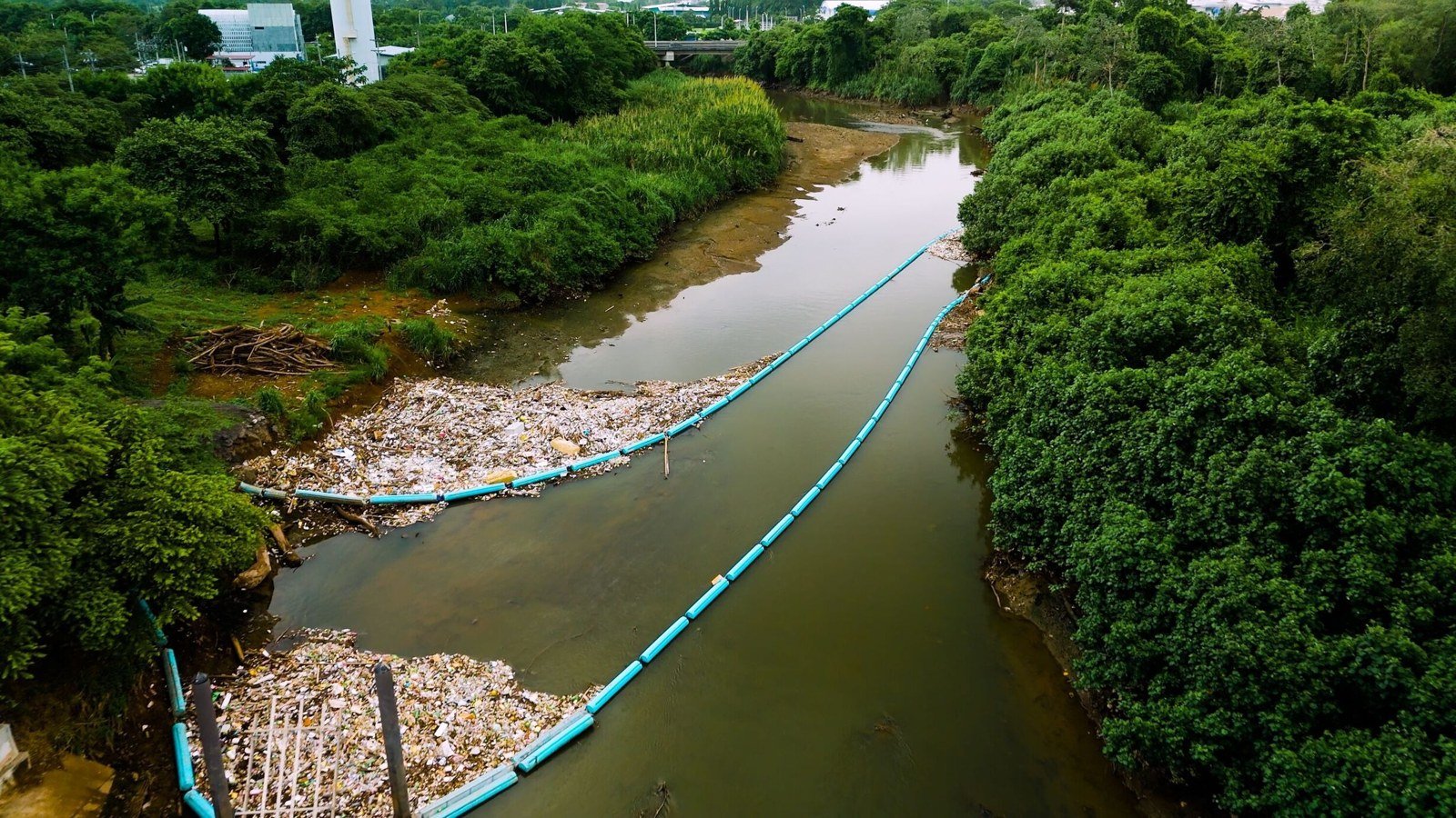 Floating blue interception barriers retaining waste in a Panama City river