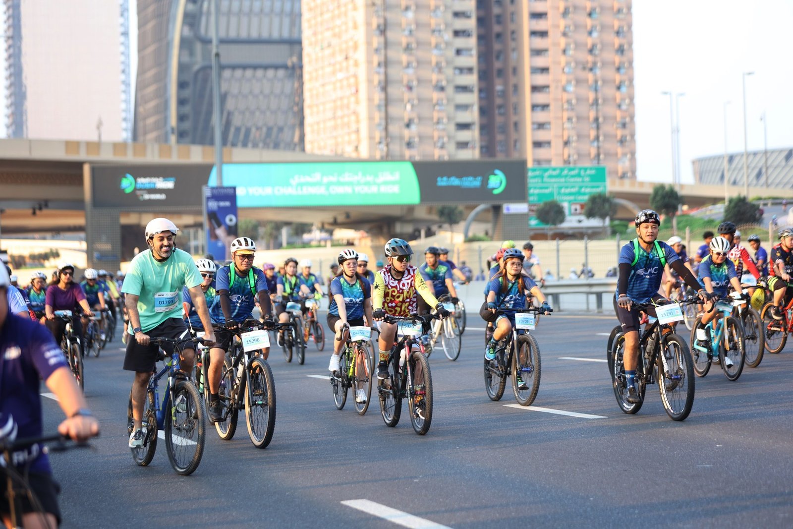 Cyclists ride along Sheikh Zayed Road with Dubai towers behind them.