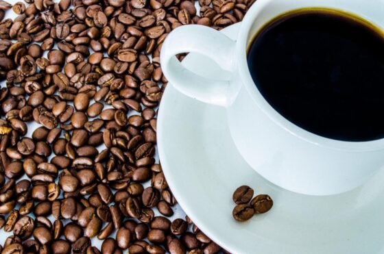 White cup of black coffee surrounded by coffee beans