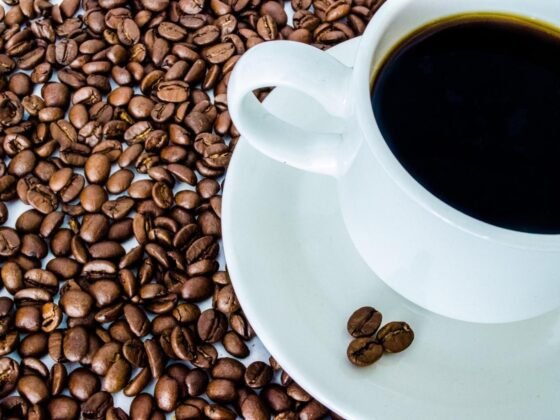 White cup of black coffee surrounded by coffee beans